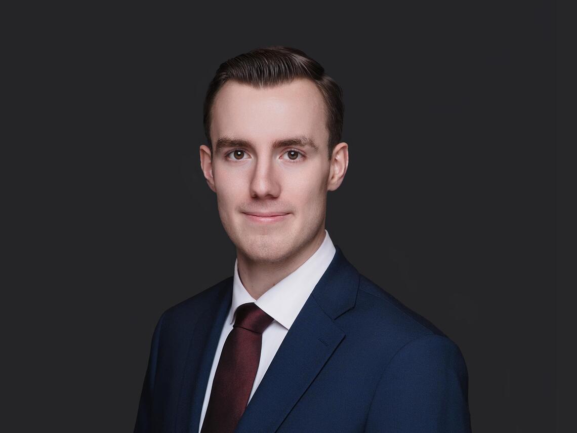 Photo of Caucasian male in blue blazer and white collared shirt with burgundy tie