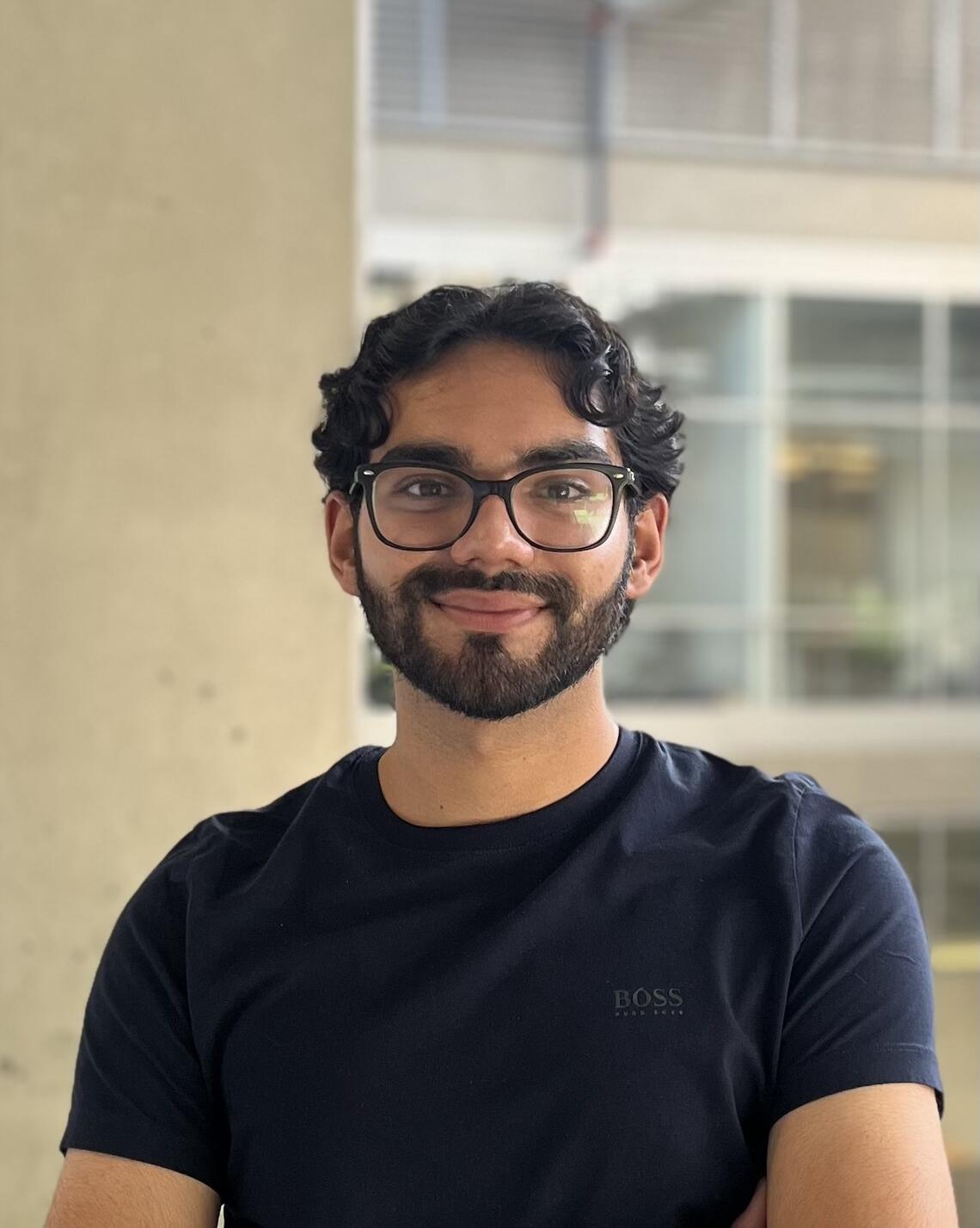 Young male, South Asian descent, wearing glasses, with facial hair and black t-shirt