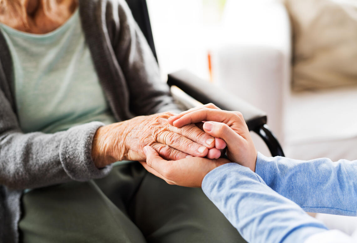 Close up of a doctor holding an elder woman's hands. both parties are clasping each other's hands