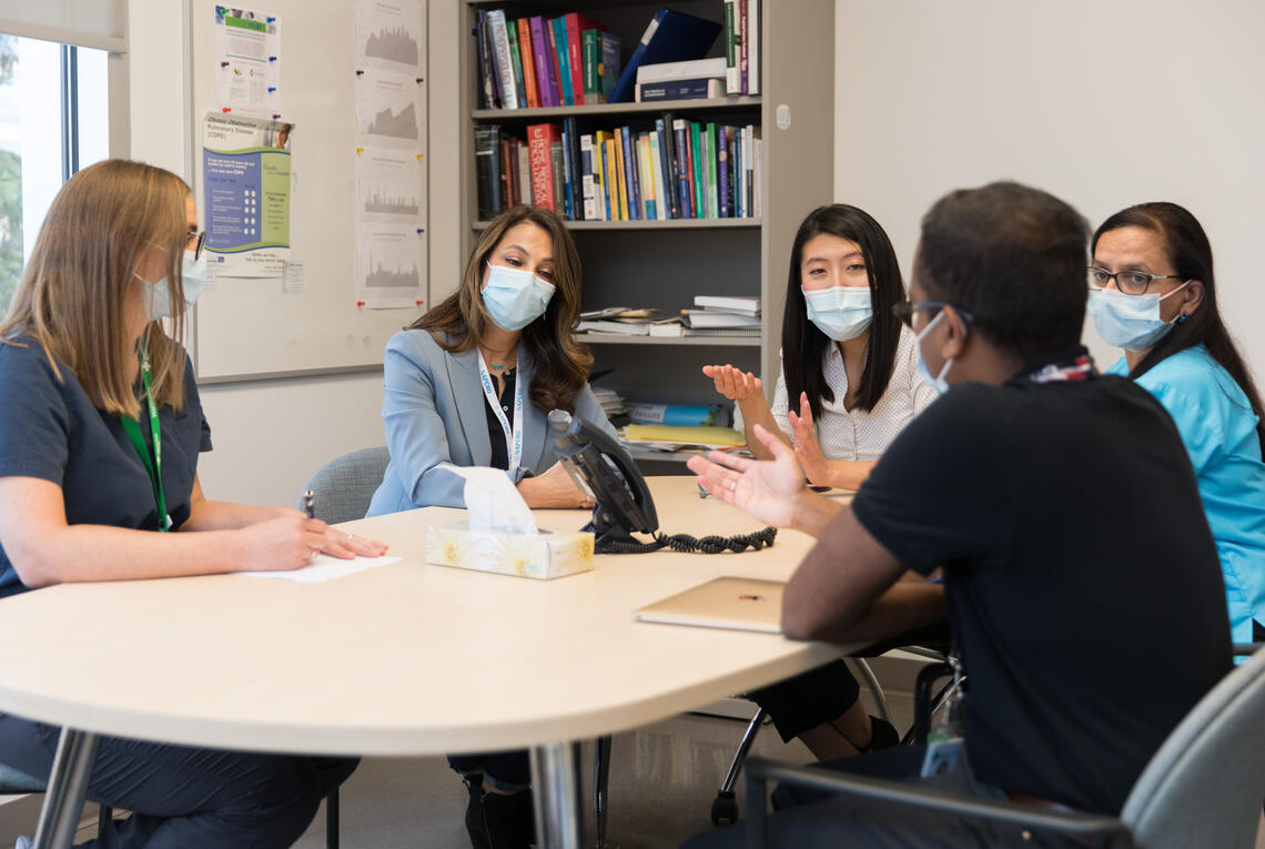 group of medical learners in discussion with teachers around table