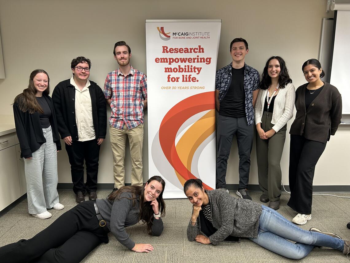 8 members of the lab from various different backgrounds smiling and posing. 
