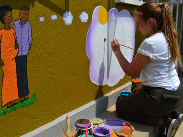 a student painting on a wall