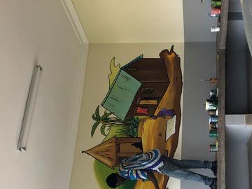 two artists painting on a health facility wall