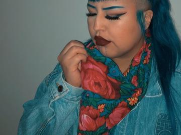 Photo of Chey with long hair wearing a blue jean jacket and floral scarf