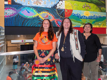 Group photo of three of the artists with the mural in the background