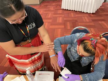 two women practicing taking dried blood sample procedure