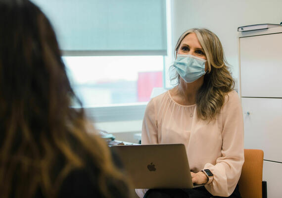 health care provider with laptop in lap, speaking to a patient