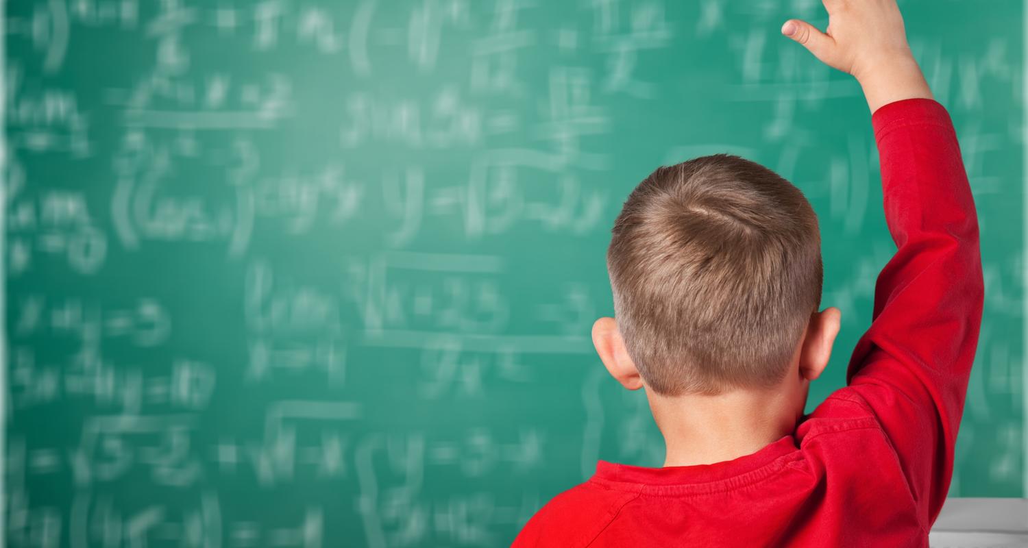 Boy in classroom with hand up