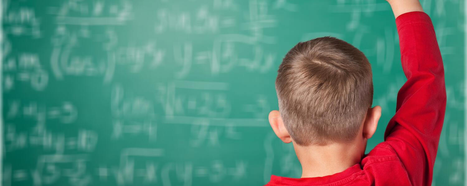 Boy in classroom with hand up