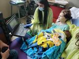 A boy in the ICU using BCI, with a researcher helping