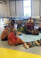 group of people sitting in a circle on the floor smiling