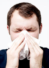 Man with a cold blowing nose