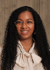 Dr. Case smiles towards the camera. She is wearing a cream coloured blouse with a decorative tied bow at the neck. 