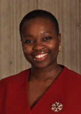 Dr. Case smiles into the camera. She is wearing a red vest with a brooch on her left hand side. 