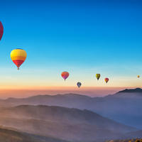 Hot balloons floating over mountainous landscape