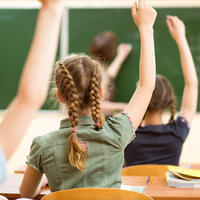 Children with hands up in classroom