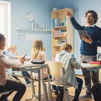 Teacher conducting a lesson in a classroom with seated children