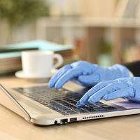 Person typing on keyboard wearing protective gloves