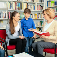 Teacher speaking with mom and child in classroom