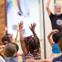 kids with both hands up in a classroom