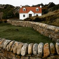 Country house with winding stone wall in front of it