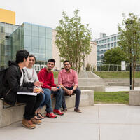 Students sitting outside on the main UofC campus