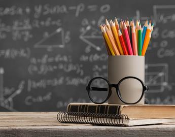 Teachers desk: pens, glasses, books.
