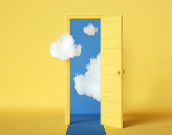 Yellow door opening from a yellow room onto a cloudy blue sky.